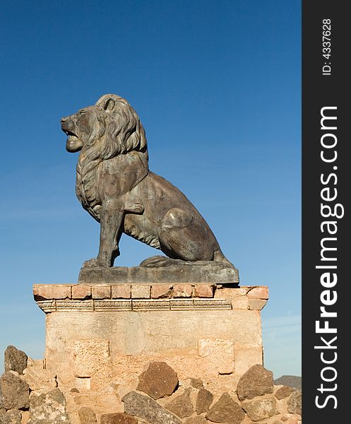 Bronze lion on aged concrete and stone pedestal against blue sky. Bronze lion on aged concrete and stone pedestal against blue sky.