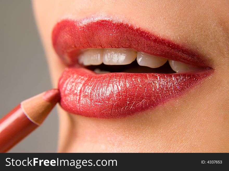 Applying cosmetics on the beautiful woman's lips. Applying cosmetics on the beautiful woman's lips