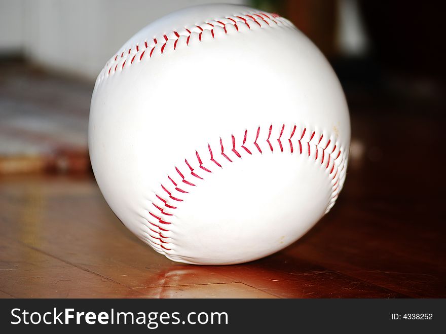 Close up of baseball sitting indoors on the hardwood floor. Close up of baseball sitting indoors on the hardwood floor.