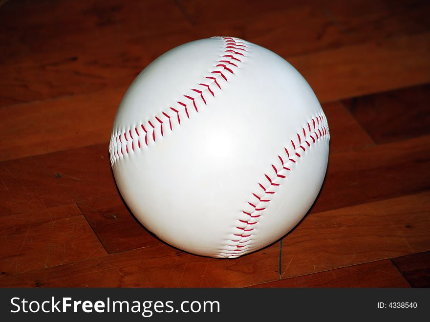 Close up of baseball sitting indoors on the hardwood floor. Close up of baseball sitting indoors on the hardwood floor.