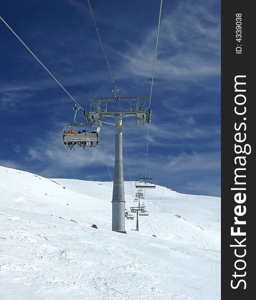 Skiers lifts to a peak of a mountain. Skiers lifts to a peak of a mountain