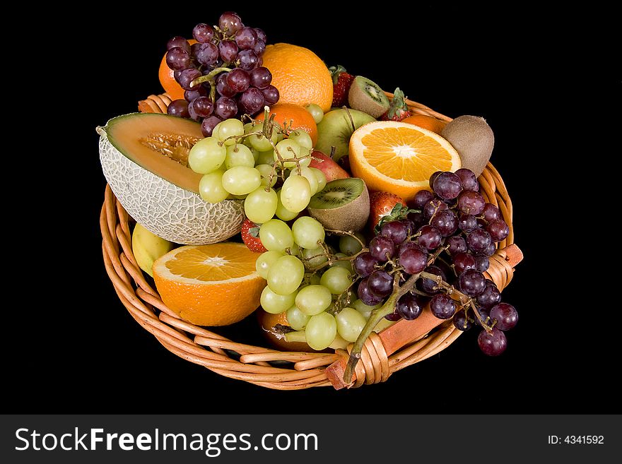 Fruit basket with many fruits before a black background