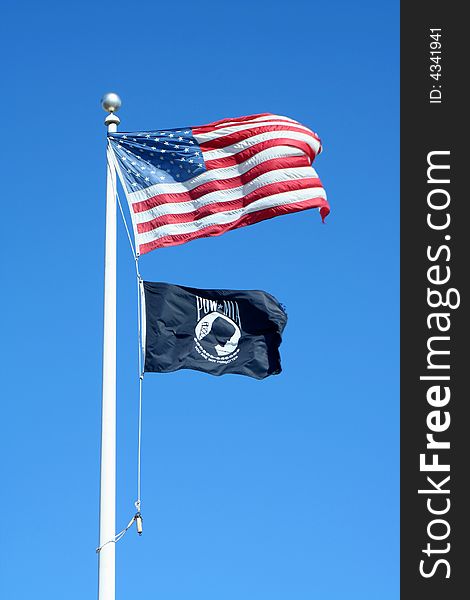 American and POW flags against a blue sky