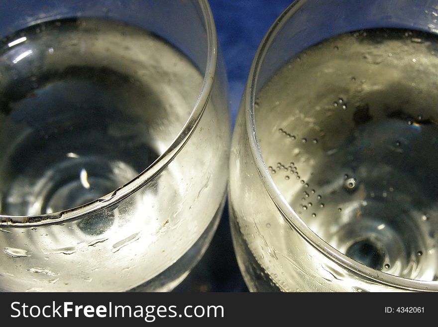 Close-up of two champagne glasses filled with bubbly on a blue background. Close-up of two champagne glasses filled with bubbly on a blue background