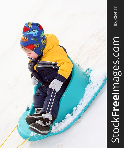 Young Boy Sledding in fresh snow in colorful outfit. Young Boy Sledding in fresh snow in colorful outfit