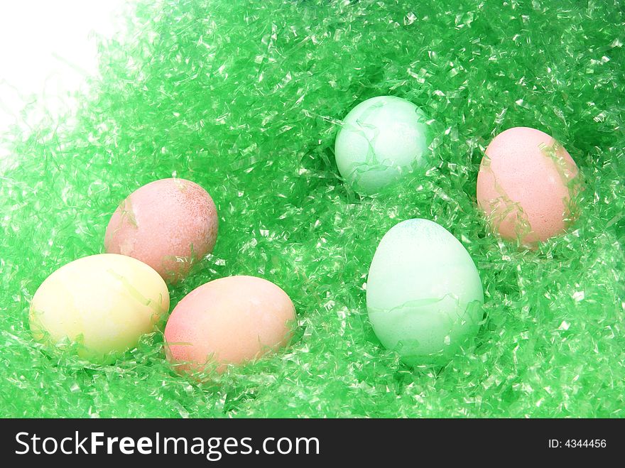 Multiple pastel colored easter eggs on green easter grass