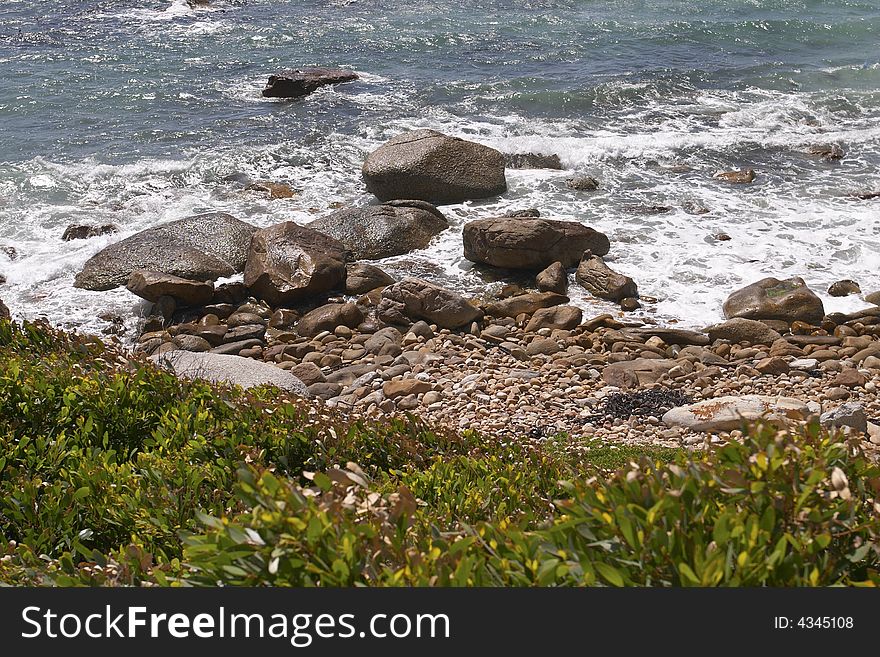 A detail from a pebble beach with rocks and breakers, Cape Town. A detail from a pebble beach with rocks and breakers, Cape Town.