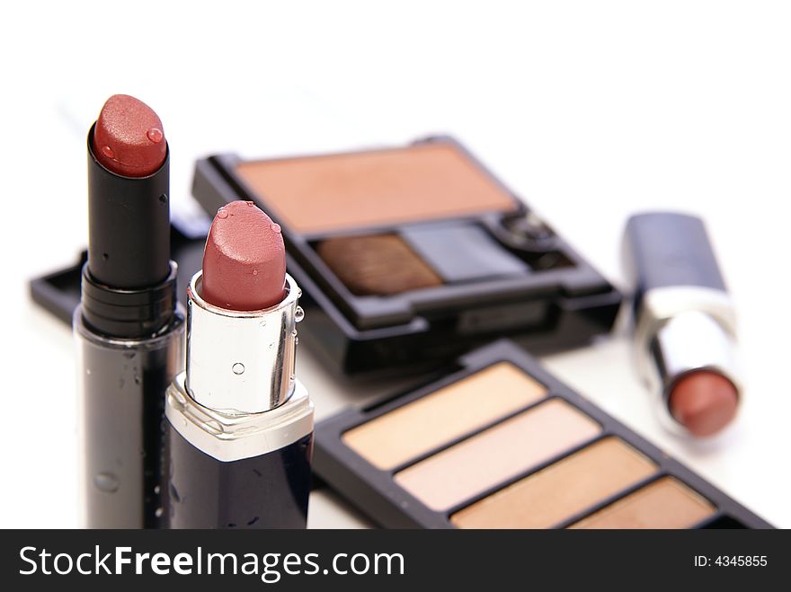 Moist lipsticks in earth tones with related makeup and cosmetics in the background