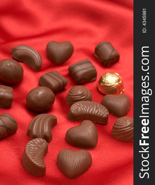 Assortment of Valentines chocolates on red silk background