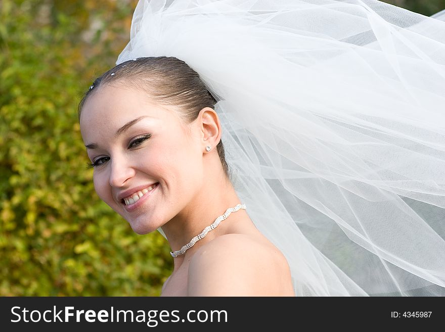 A happy bride and a flying downwind veil. A happy bride and a flying downwind veil