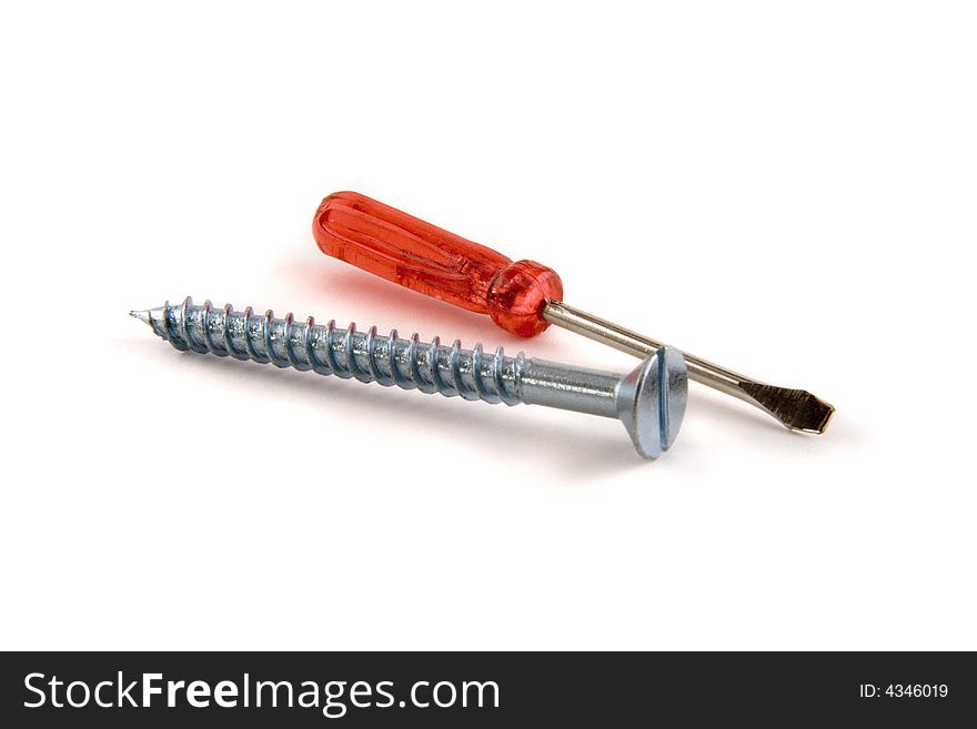 An isolated picture of a very small, red-handled screwdriver lying next to a large screw.