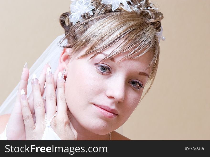 Beautiful bride thingfully puts on an ear-ring. Beautiful bride thingfully puts on an ear-ring