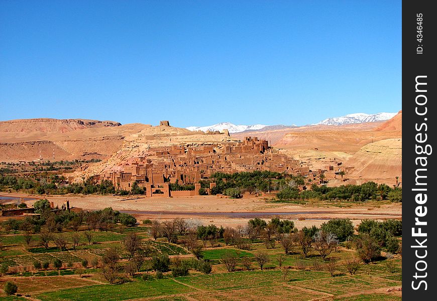 Ksar of Ait Ben Adou with snowed mountains in the background and some fields at the front. Ksar of Ait Ben Adou with snowed mountains in the background and some fields at the front