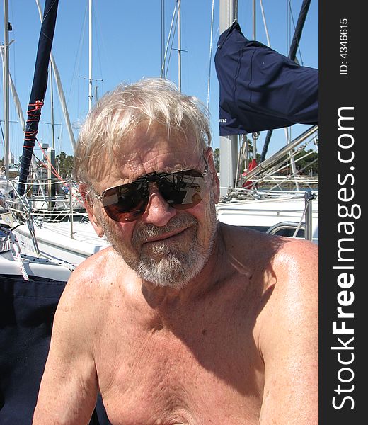Older confident  seaman captain smiling boat at marina  sunglasses on shirtless in sun. Older confident  seaman captain smiling boat at marina  sunglasses on shirtless in sun