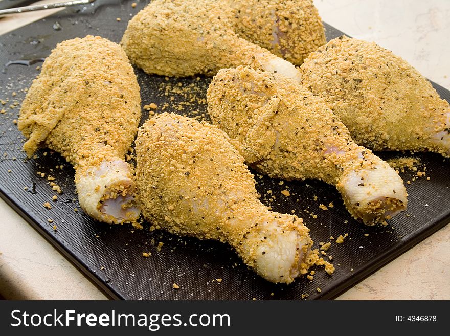 Coated raw chicken drumsticks on desk