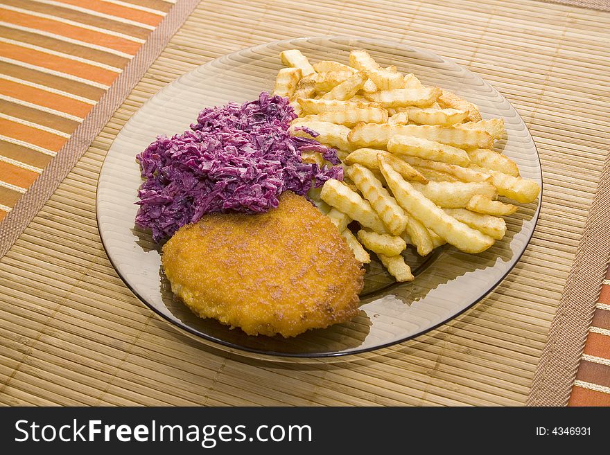 Chicken chop with french fries and salad on the bamboo desk