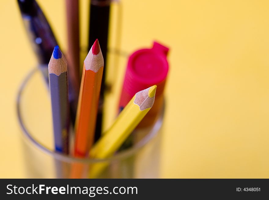Pencils with a glass on the yellow background