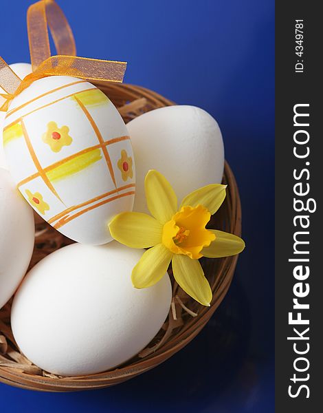 Easter eggs with yellow flower on blue background.