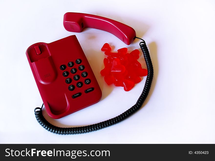 Red telephone with gummy hearts bonbons over white background. Red telephone with gummy hearts bonbons over white background