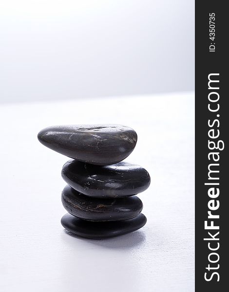 Four stapled, round, smooth black stones. Zen-Style. White background. Reassuring. Four stapled, round, smooth black stones. Zen-Style. White background. Reassuring.