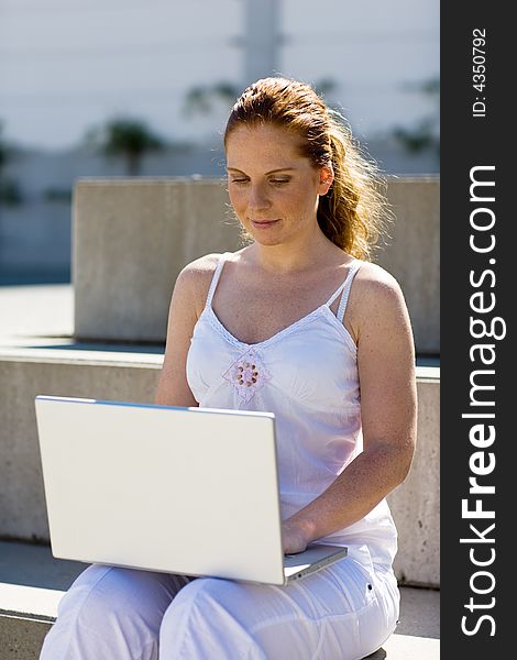 Woman (a student?) sitting alone on a stair, typing on the silver laptop. It's lucid and summery. Woman (a student?) sitting alone on a stair, typing on the silver laptop. It's lucid and summery.