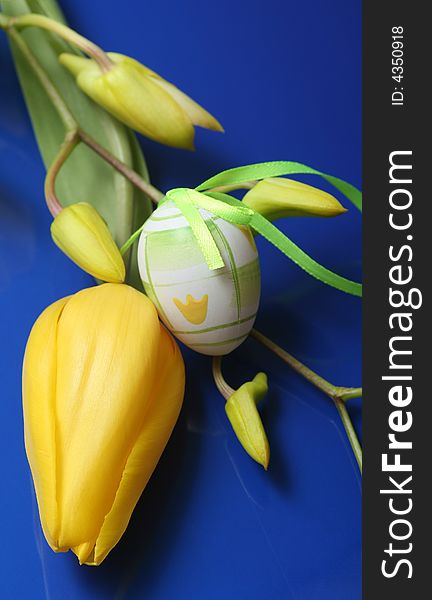 Easter egg with yellow tulip on blue background.