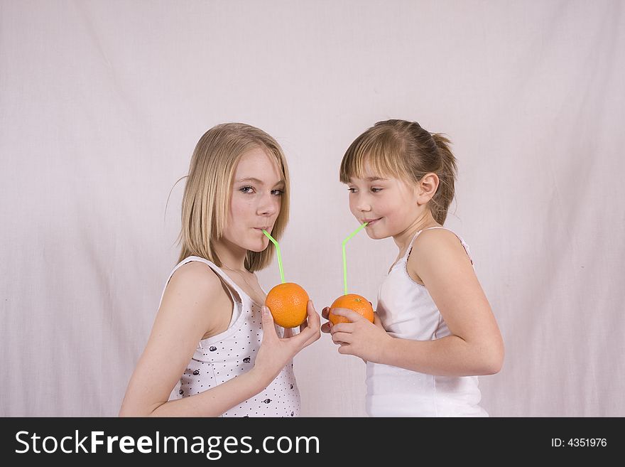 Two girls drinking juice from an orange. Two girls drinking juice from an orange