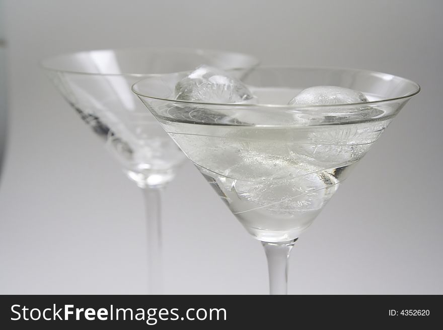 Two martini glasses, one with vermouth and ice