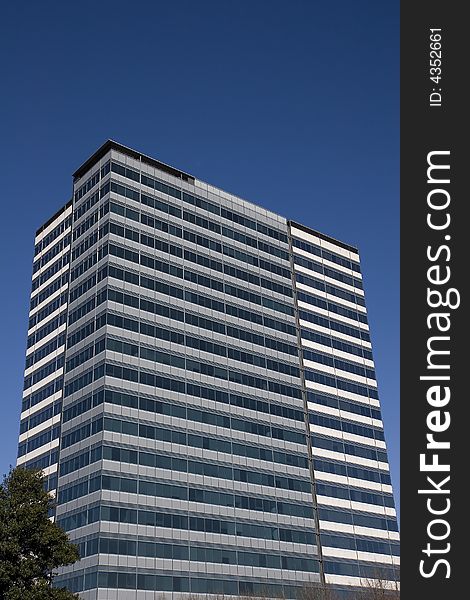 A building of grey concrete and blue glass against the sky. A building of grey concrete and blue glass against the sky