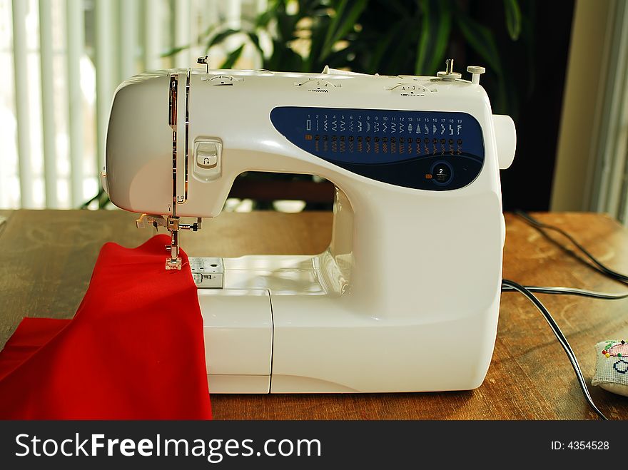 Sewing machine on table with red cloth.