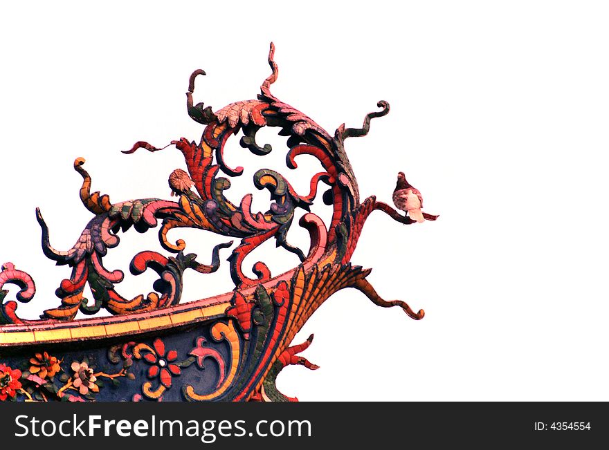 Colorful delicate phoenix tail wood carvings on a Buddhist Temple.phoenix tail shaped wood carving where a pigeon stand perching. Colorful delicate phoenix tail wood carvings on a Buddhist Temple.phoenix tail shaped wood carving where a pigeon stand perching.