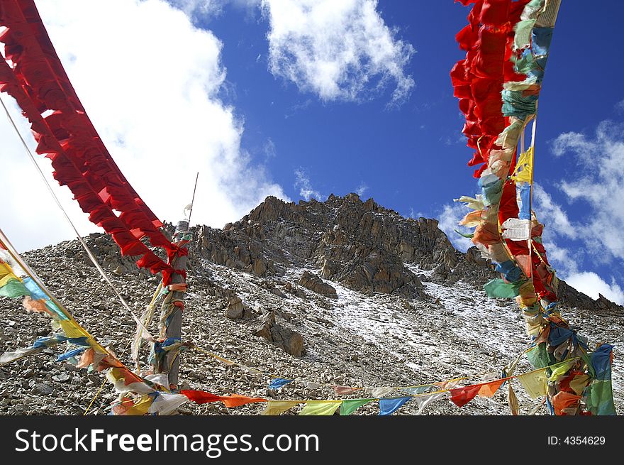 Prayer flag is waving with the blue sky and snow mountain background