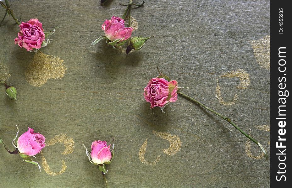 A dried rose placed on top of an old  green wood table. A dried rose placed on top of an old  green wood table