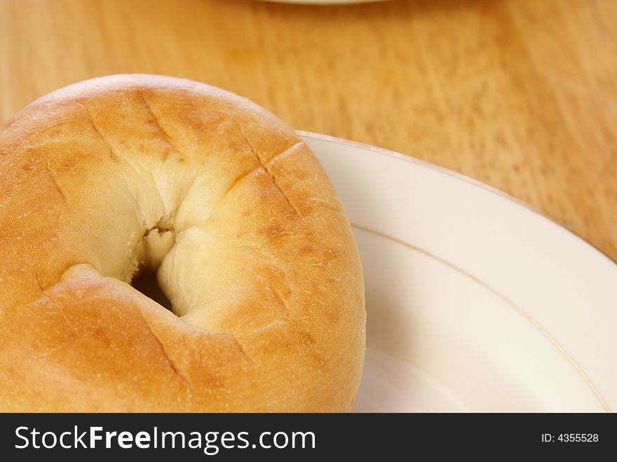 Plain bagel on white plate and wooden table