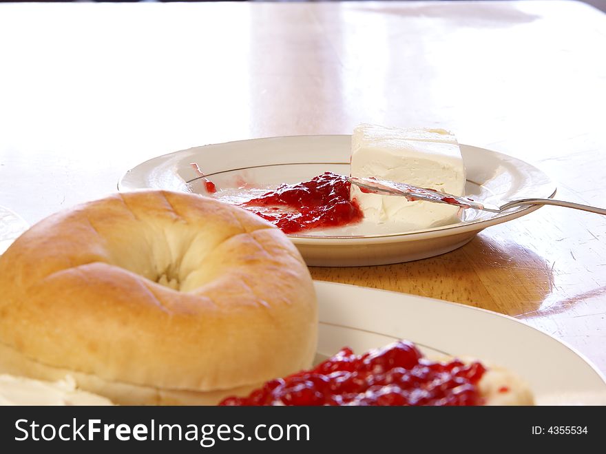 Cream cheese and strawberry preserves with fancy butter knife. Plain bagel blurred in the foreground. Cream cheese and strawberry preserves with fancy butter knife. Plain bagel blurred in the foreground.