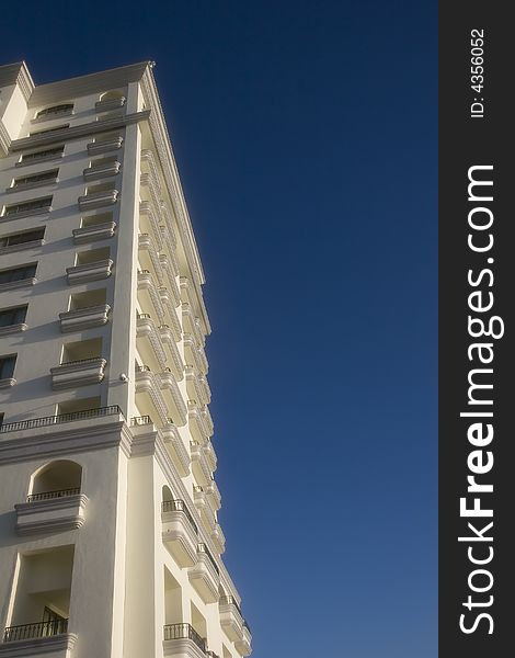 A white hotel with balconies against a  blue sky. A white hotel with balconies against a  blue sky