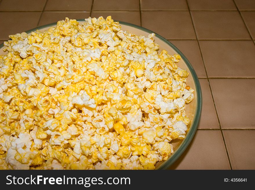 A freshly buttered bowl of popcorn for use as a background or party announcement. A freshly buttered bowl of popcorn for use as a background or party announcement