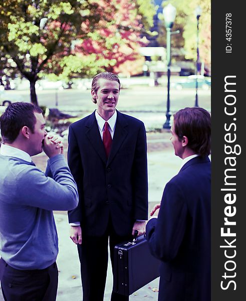 Three business men talking standing outdoors. Three business men talking standing outdoors