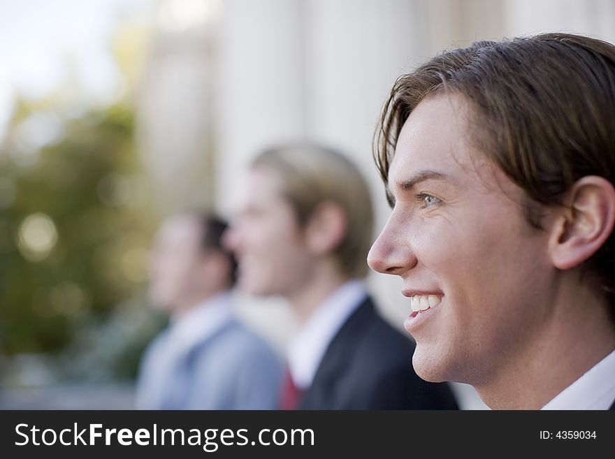 Three business men standing and smiling in same direction. Three business men standing and smiling in same direction