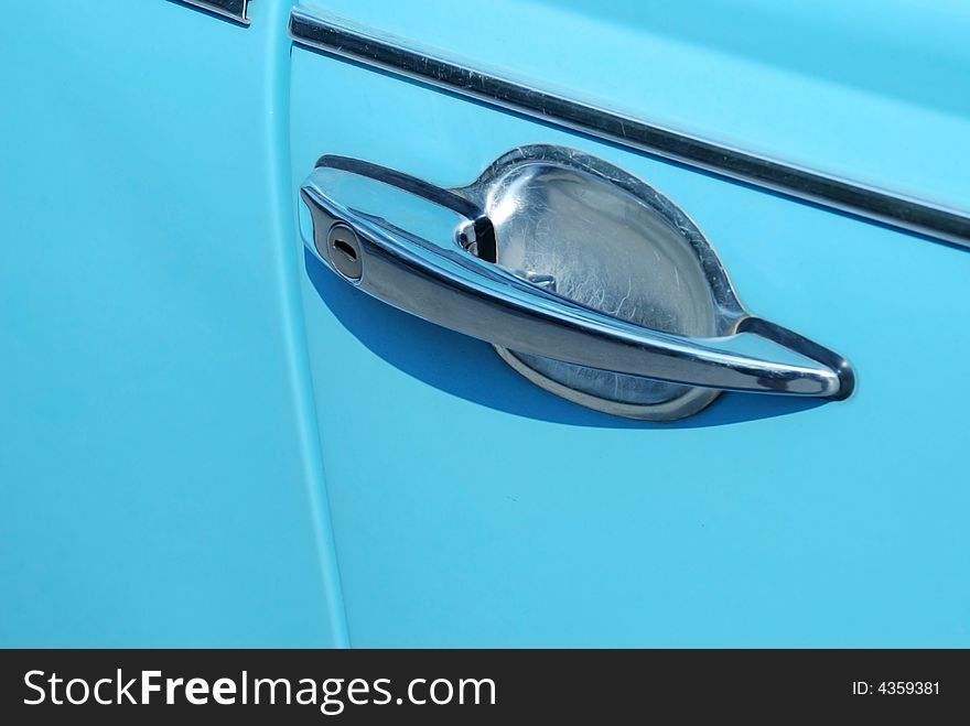 A detail image of a door handle on a light blue german vintage car