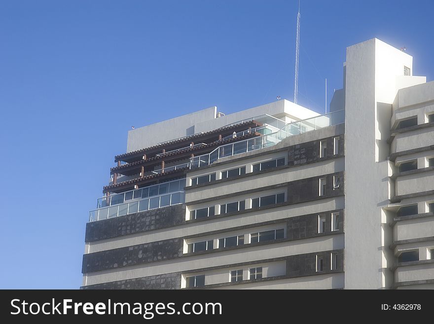 A white luxury resort hotel against a blue sky. A white luxury resort hotel against a blue sky