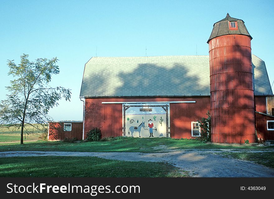 An old barn and silo has a new mural on the entrance way. An old barn and silo has a new mural on the entrance way