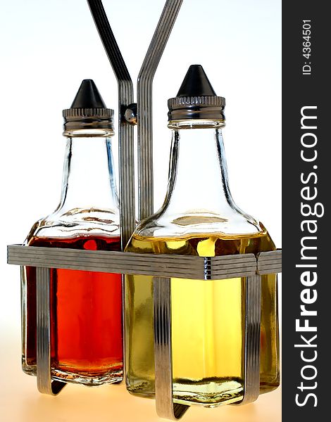 Oil and vinegar bottles in a wire rack on white background. Oil and vinegar bottles in a wire rack on white background.