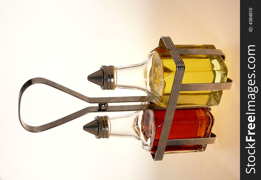 Oil and vinegar bottles in a wire rack on white background. Oil and vinegar bottles in a wire rack on white background.