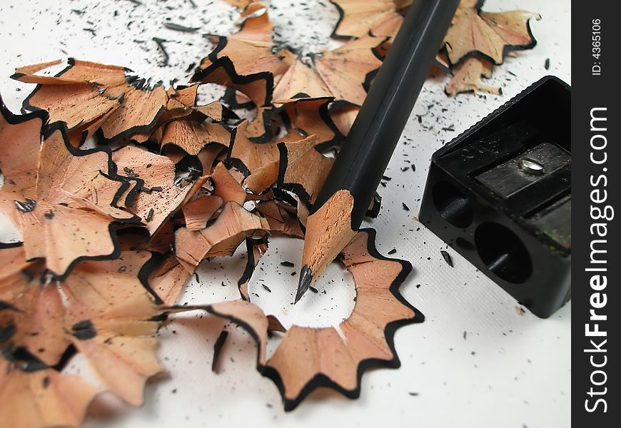 Macro shot of sharpened, wood pencil and sharpener with shavings. Macro shot of sharpened, wood pencil and sharpener with shavings