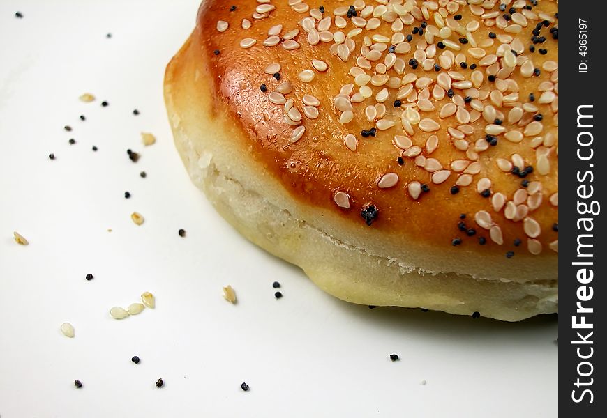 Macro shot of a golden brown sesame and poppy seed bun against a white background. Macro shot of a golden brown sesame and poppy seed bun against a white background