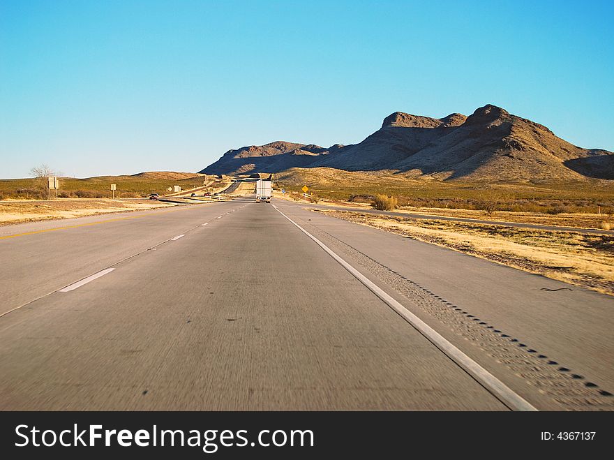 Driving on Interstate 10 as the sun sets to the west casting a shadow on the arid desert mountains in West Texas. Driving on Interstate 10 as the sun sets to the west casting a shadow on the arid desert mountains in West Texas.