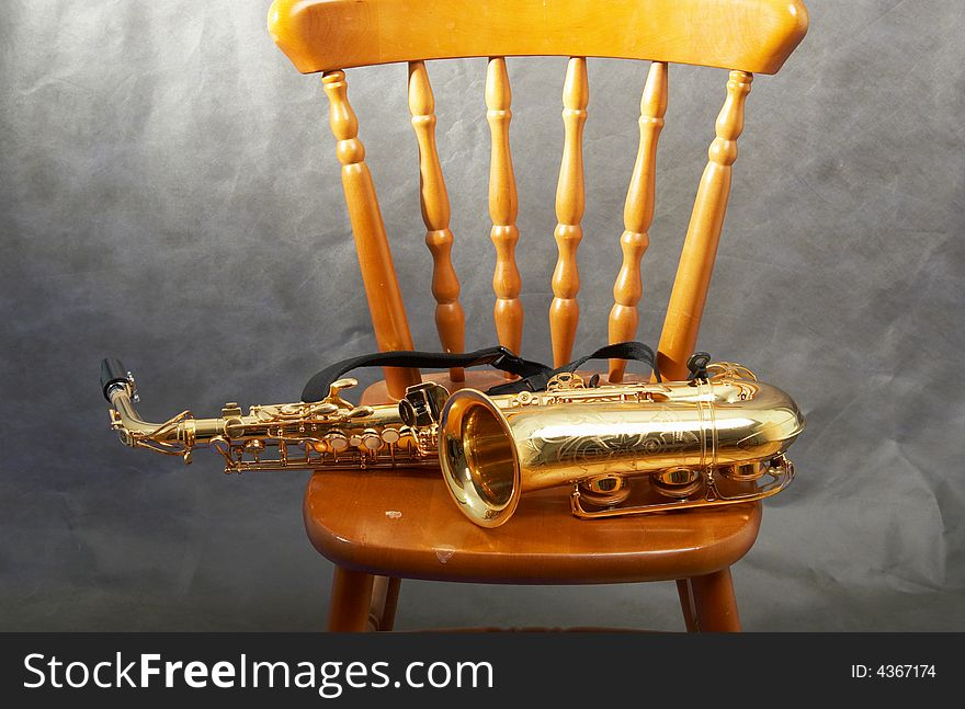 The saxophone lays on a chair. The saxophone lays on a chair