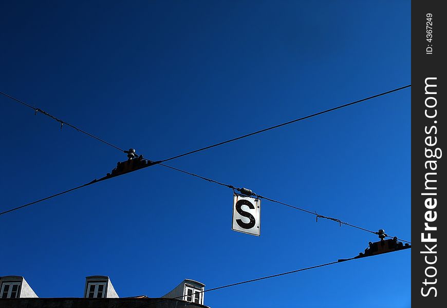 Tram wires in front of a clear blue sky.