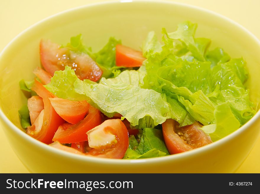 Bowl of fresh salad on yellow background